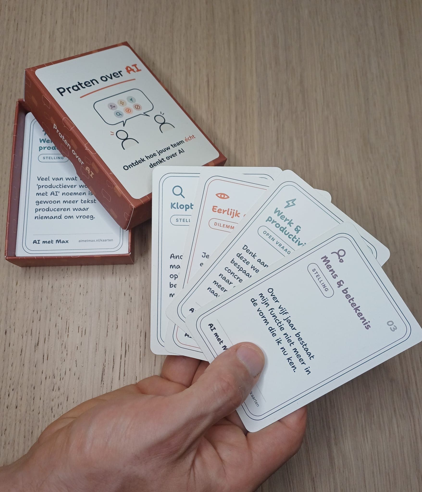 Praten over AI: de gesprekskaarten in de hand met het doosje op tafel